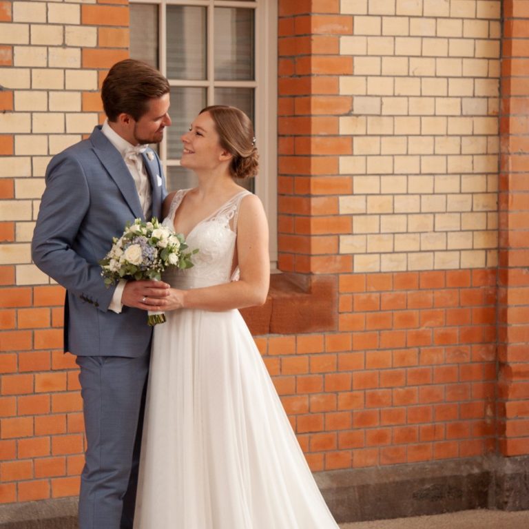 Hochzeitsfotografie Wuppertal Brautpaar mit Brautstrauß vor Backsteinfassade in Wuppertal